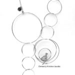 Halsketting in zilver met ringen van verschillende formaten. in één van de ringen zit een figuurtje te kijken